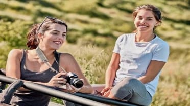 Girls smiling and taking photos on a jeep Girls smiling and taking photos on open roof jeep safari